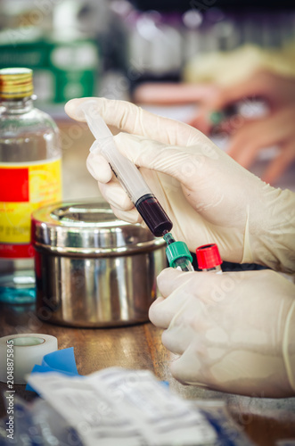 Nurse wearing white medical gloves is drawing blood from patient's arm for examination or PRP procedure. Concept of laboratory research, medicine, analysis.