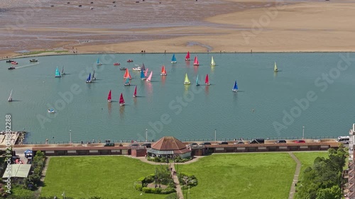 Sailing dinghies on West Kirby marine lake with Coronation Gardens in the foreground, Wirral peninsula, Merseyside, England.