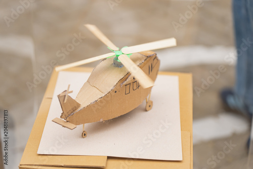 Foto Handmade cardboard helicopter model craft with wooden stick rotor blades standin