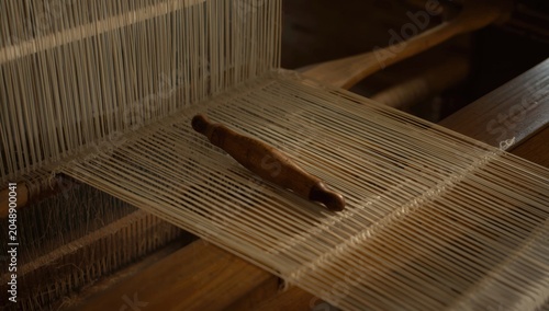 Obraz na płótnie Wooden shuttle navigating warp threads on loom