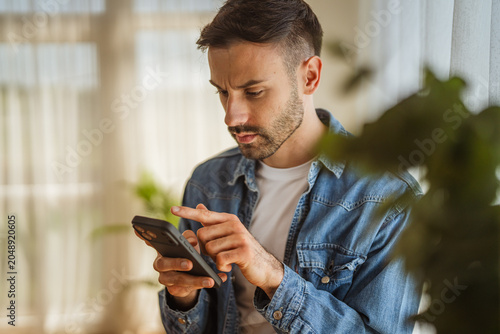 Photography Man serious concentrating using smart phone indoors for communication
