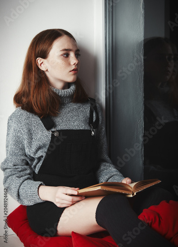 Indoors portrait of sweet small girl reading a book