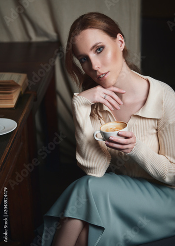 Retro (vintage) style portrait of smiling sweet young girl with book and cup of coffee (cappuccino)
