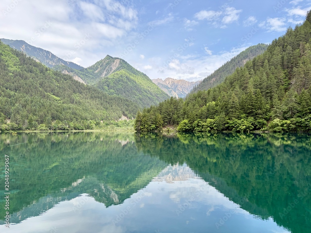 Fototapeta premium Stunning reflection of lush green mountains on the turquoise lake in Jiuzhaigou National Park, China - in June, summer