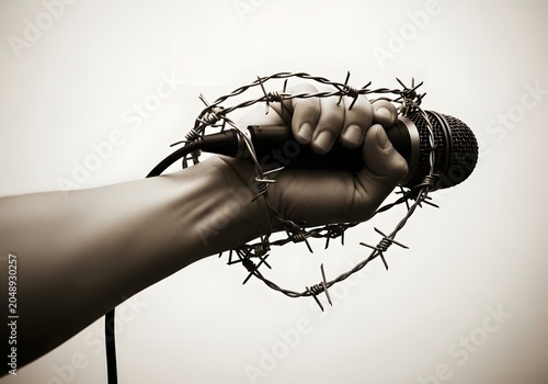 Hand holding a microphone wrapped in barbed wire