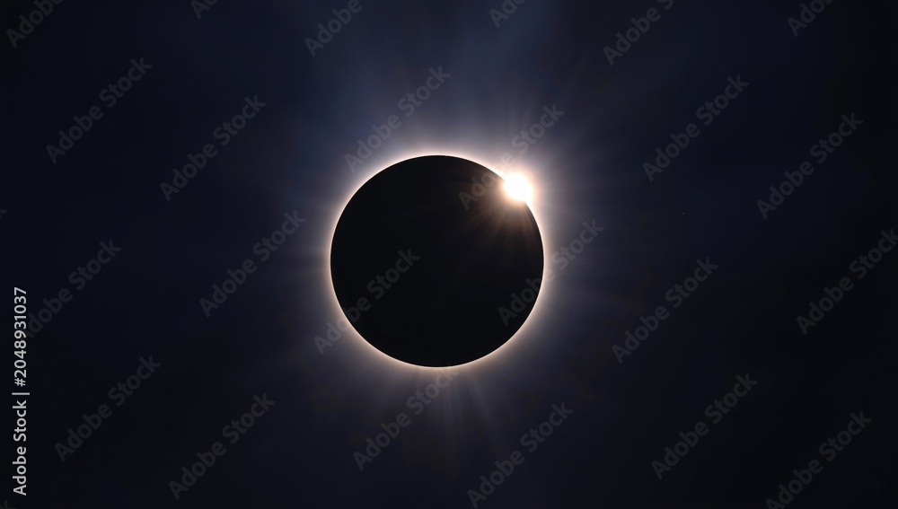 Obraz premium Sunlight halo shining through eclipse silhouette