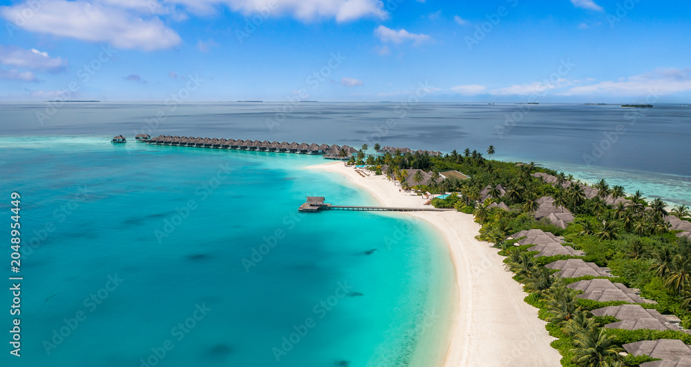 Fototapeta premium Stunning aerial Maldives island scenery. Overwater villas and turquoise lagoon from above. Tropical paradise seascape reef and white sand. Luxury travel destination banner, summer vacation drone view