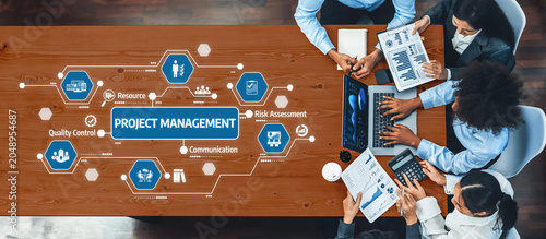 Photography A top-down view of a diverse team engaged in project management, utilizing digital tools and presenting visual data for effective communication and strategic planning