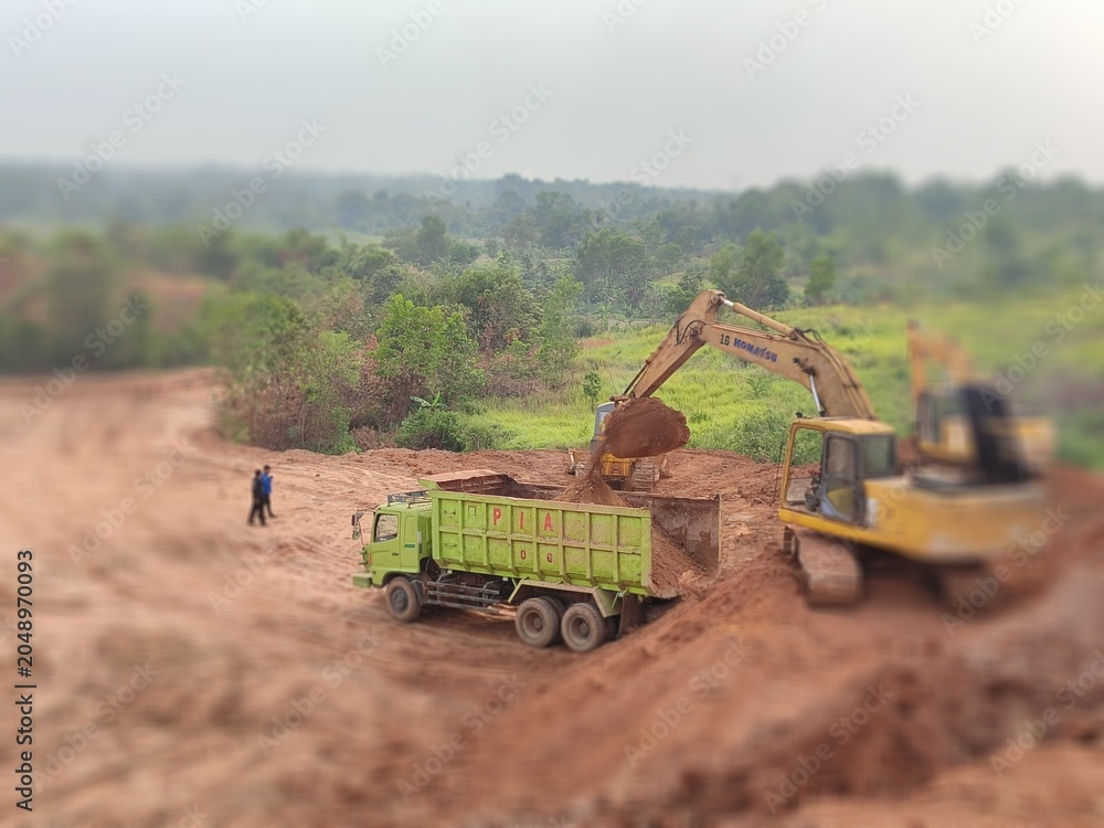 Fototapeta premium Land acquisition construction for housing development combine harvesting wheat