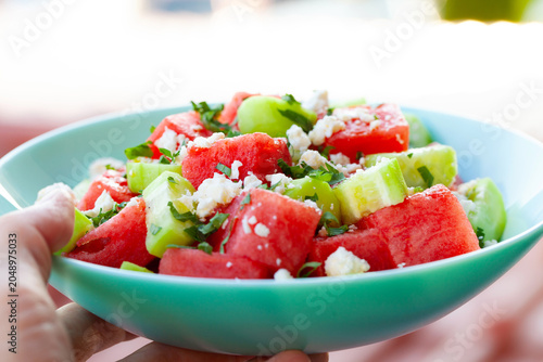 Refreshing mediterranean fruit salad held in hand for outdoor summer picnic or healthy meal. Close up.