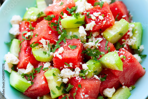 Healthy fresh organic watermelon salad with mint feta cheese and cucumber closeup in blue bowl. Close up.