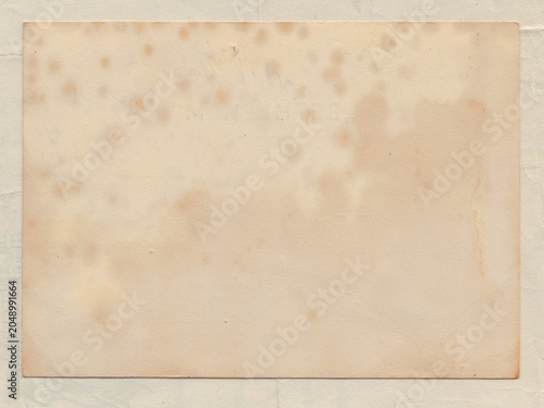 A sheet of old paper showing foxing, characterized by scattered, light brown spots and irregular stains. The paper has a yellowed, aged appearance, typical of antique documents. 