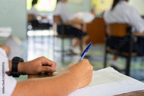 High School Student Taking Standardized Test with Concentration on Wooden Desk
