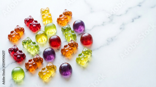 Colorful gummy bear shaped children's vitamins on marble surface in various colors, concept of kids health and nutrition supplements.