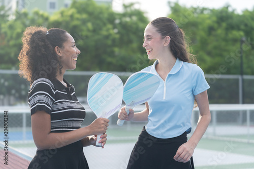 Valokuva Female pickleball players laughing with paddles on court