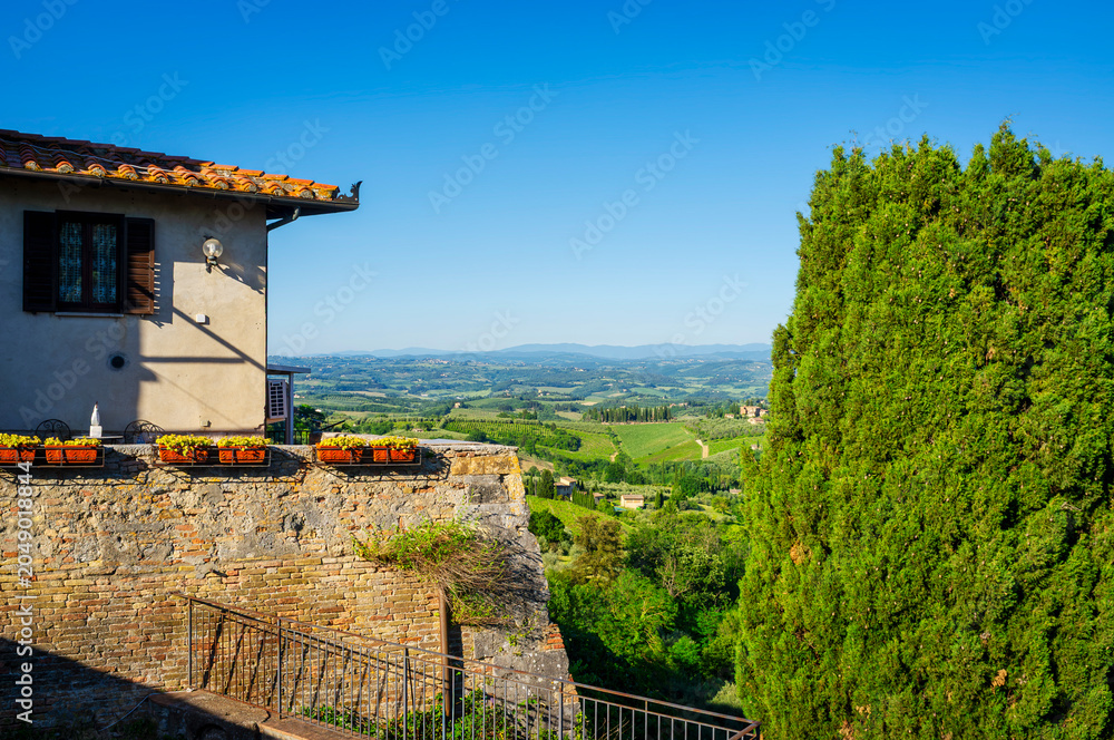 Naklejka premium Panoramic view of the hills and countryside surrounding the village of San Gimignano (Tuscany village, Italy), covered by olive trees and vineyards, during early summertime.