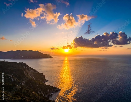 Golden sunset over ocean with mountains and radiant sunbeams