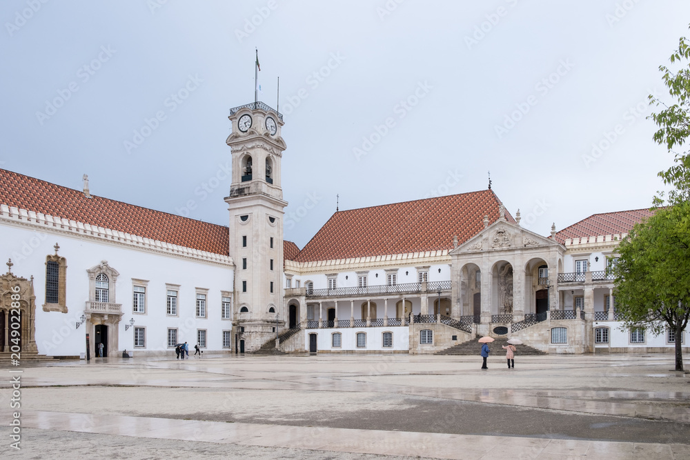 Fototapeta premium Coimbra, Portugal – Overcast view of the Courtyard of the Schools, featuring the baroque clock tower and Via Latina gallery at the University of Coimbra, Portugal's oldest university (1290).
