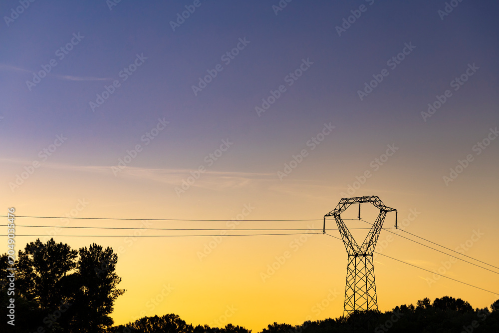 Obraz premium High voltage pylon in the French countryside stands out against the sky at sunset. 400 kV High voltage electric power grid.