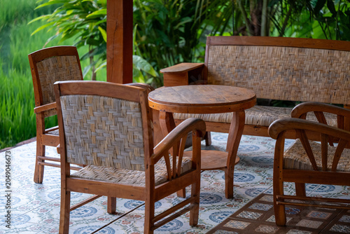 Javanese wooden furniture on patio looking out at green rice field