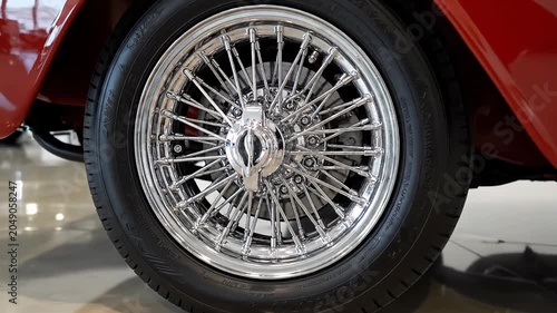 Chrome wire spoke wheel of a red vintage car.