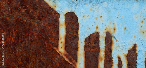 Close-up of a weathered metal surface featuring rust corrosion over faded blue paint. Abstract Rust Texture with Blue Paint and Urban Silhouette Pattern