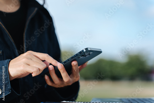 Foto Close Up Finger Tapping Modern Smartphone with Triple Camera Outdoors