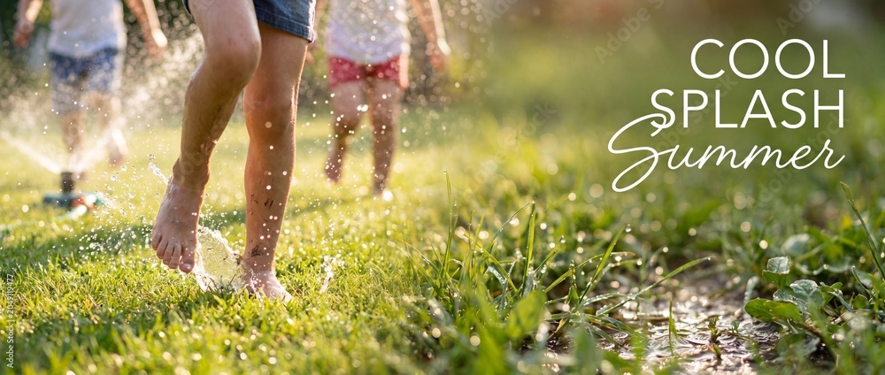 Fototapeta premium Children running barefoot splashing water on lush green backyard grass garden lawn with sprinkler spraying drops in sunny summer backyard playground joyful happy childhood youth lifestyle concept.