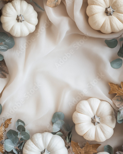 Neutral Autumn Background with White Pumpkins and Flowing Linen Fabric