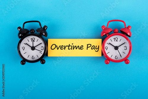 Alarm clock and Overtime Pay on blue background