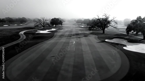 Black and White Drone Shot of Foggy Golf Course with Trees and Sand Traps on a Gloomy Day