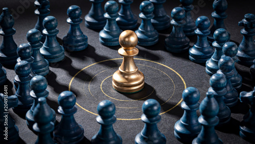 Shiny golden chess pawn standing in the center of dark blue wooden pieces on board