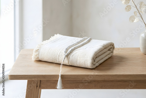 White tasbih prayer beads resting on folded textured blanket on wooden table