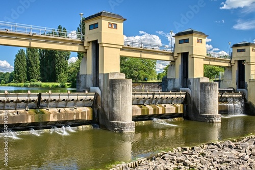 Foto River weir water gate structure for flood control and river regulation under a blue sky with clouds