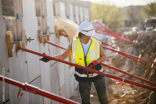 Female construction worker inspecting concrete wall bracing