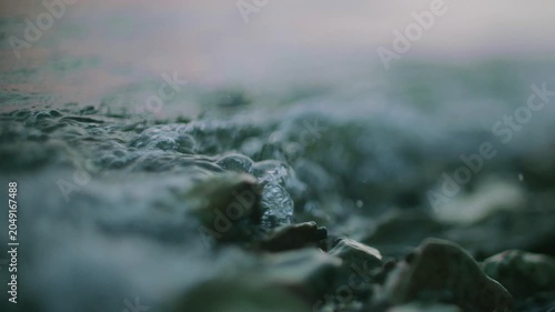 Wet dark rocks beside softly rippling water