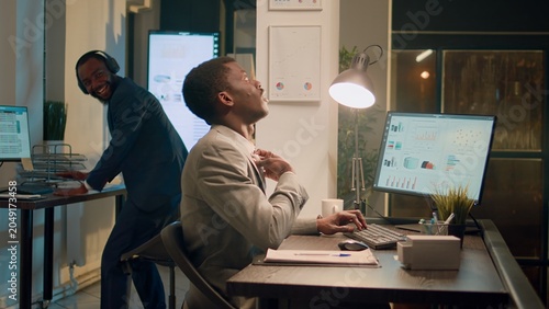 Foto Computer operator fed up with coworker having fun at work pretending to beat drums during nightshift