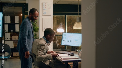 Foto Office manager interrupting unattentive employee listening to music while solving tasks to show him mistake he needs to fix