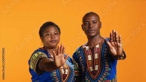Foto African american couple doing stop symbol with palm, expressing negativity and indicating refuse over orange background