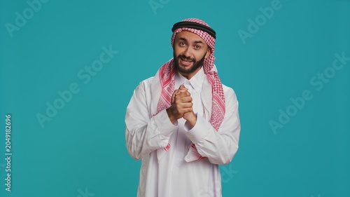 Fotografía Hopeful arab man begging and pleading for something, holding hands in a prayer and showing belief