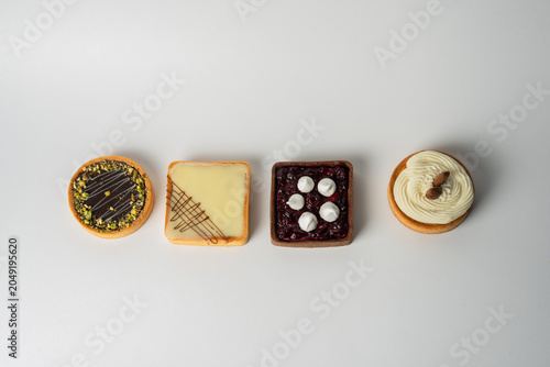 Φωτογραφία Four elegant tarts: chocolate-pistachio, vanilla-almond, cream with cherry jam, and white chocolate, each with a buttery, flaky crust and indulgent, flavorful filling