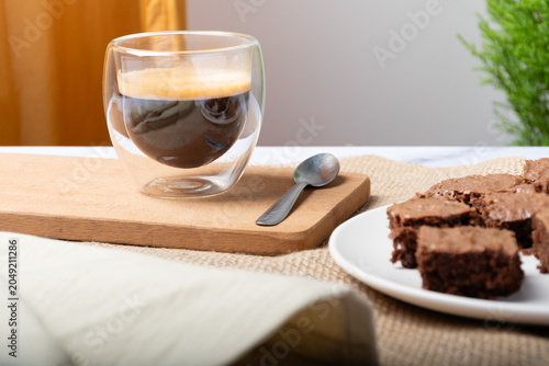 Chocolate brownie cut into pieces and a cup of espresso.