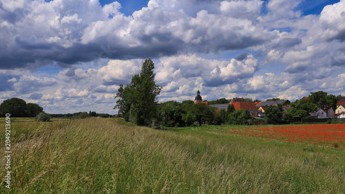 Radfahrer auf dem Elster-Radweg durch eine idyllische Wiesenlandschaft unter einem spektakulären Wolkenhimmel, Ermlitz, Schkopau, Saalekreis, Sachsen-Anhalt, Deutschland