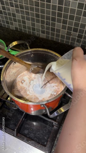 Coconut milk liquid is poured into the bowl of chocolate cake mixture