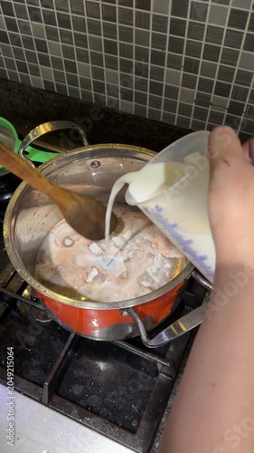 Coconut milk liquid is poured into the bowl of chocolate cake mixture