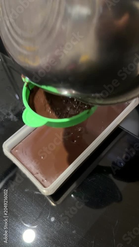 Hand Straining Ground Chocolate Into Boiling Pot on Kitchen Stove