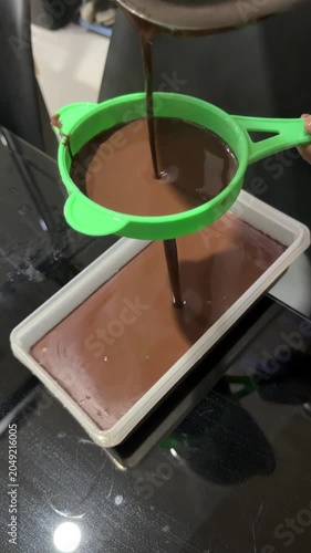 Hand Straining Ground Chocolate Into Boiling Pot on Kitchen Stove