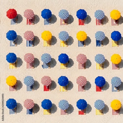 Aerial pattern of colorful beach umbrellas and loungers on sand