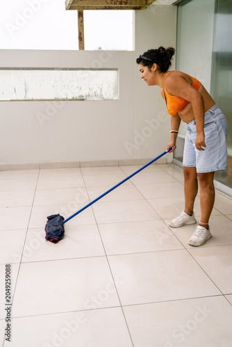 Woman cleaning balcony floor in preparation for summer