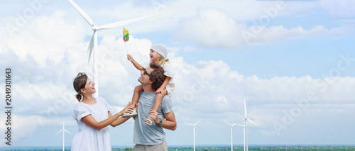 Photography Joyful family embraces outdoor playtime featuring colorful windmill and toy during bright day under partly cloudy sky—perfect for family memories or advertising fresh air activities